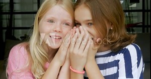 Two young girls whispering and telling secrets to each other