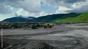 Industrial excavation machinery is working at industrial quarry. Industrial machinery used for excavation of valuable material. Industrial excavation machinery loading dump truck with precious metals