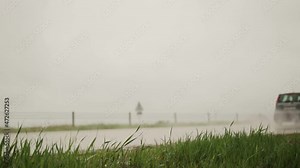 The car drives on a wet road in the rain. Slippery road and poor visibility on the road, in the background. Slow motion