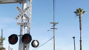 Level crossing warning signal in USA. Crossbuck notice and red traffic light on rail road intersection in California. Railway transportation safety symbol. Caution sign about hazard and train track.