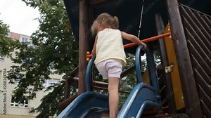 Barefoot kid girl play climb the slide on park playground for children