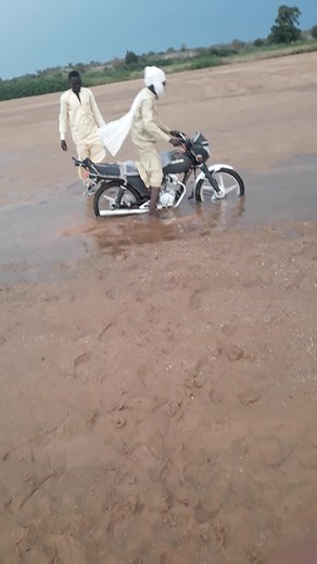 Struggling to Push a Motorcycle Out of the Mud