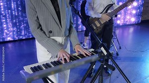 Keyboard player performing live music on stage with a band, illuminated by colorful led lights, creating a vibrant and energetic atmosphere