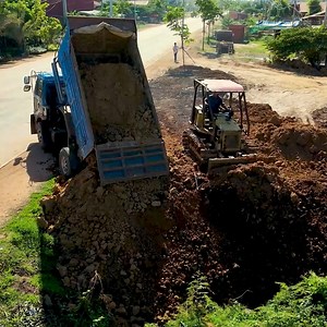 The skilled operator deftly maneuvers the bulldozer, pushing soil into the water prior to unloading the dump truck. | BulldozeR PoweR