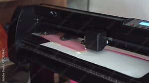 Cutting plotter. Plotter cuts pink vinyl, film. Laser cuts vinyl, film. Industrial equipment for cutting vinyl and film.