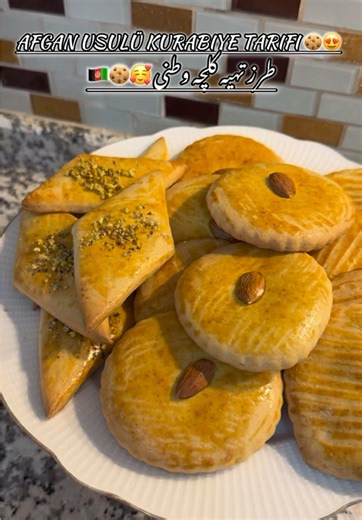 فارسی،دری⬇️Türkçe ⬇️ Afghan cookies طرز تهیه کلچه وطنی 🥰🇦🇫 •\tشیر: نیم لیوان •\tروغن: نیم لیوان •\tتخم‌مرغ: ۳ عدد •\tشکر: ۱.۵ لیوان •\tبیکینگ پودر ۱ پاکت ۱۰ گرمی •\tوانیل ۱ پاکت ۱۰ گرمی •\tنمک: یک پنس . هل یک قاشق چایخوری . سودا (جوش شیرین )یک قاشق چایخوری •\tآرد سفید: ۵–۶ گیلاس (تا خمیر نرم شود) زردی تخم مرغ بر روی کلچه بادام و پسته برای تزیین فر را از قبل با درجه ۱۸۰ سانتی گراد گرم کنید و بگذارید ۱۵ تا ۲۰ دقیقه بپزد Afgan usulü kurabiye tarifi 🇦🇫🍪🥰 • Süt: yarım su bardağı • Yağ: yarım s