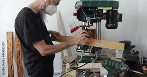 DIY Woodworking, man drilling sharp angle hole in wood plank using benchtop drill press