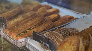 View on bakery counter with many different cakes, sandwiches and bread displayed, freshly baked pastries on a bakery shop counter. Baked baguettes and pies on showcase in bakery shop.