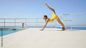 Beautiful young woman doing yoga and acroyoga by the swimming pool on her villa rooftop terrace. Yoga teacher training in the morning outdoor. Concept about sport, healthy lifestyle and wellness