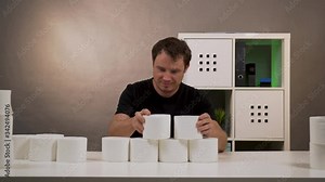 a man builds on the table a pyramid of toilet paper