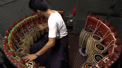 The Pat Waing is a mesmerizing Burmese percussion instrument — a set of 21 pitch‑tuned drums arranged in a carved wooden horseshoe, richly decorated with gold leaf. The musician sits in the center and plays the ensemble with fingers and palms, weaving melodies and rhythms that float across more than three octaves It’s the centerpiece of the Hsaing Waing, the traditional Burmese folk orchestra — a thrilling fusion of drums, gongs, oboes, and clappers, known for its heterophonic interplay and high