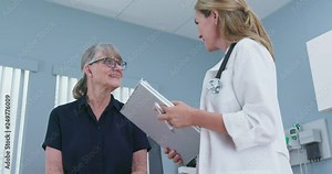Low angle view of female doctor taking medical history from senior patient in exam room. Older Caucasian woman visiting primary care physician for regular check up. Slow motion 4k