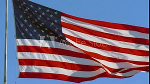 USA flag flaping in wind. Elegant Nylon American Flag Waving in the Wind. Close-up of an American flag flying in the wind against a background of clear blue sky. Close up of American flag waving, 4K.