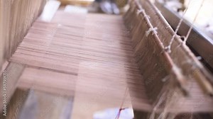 Hands of Asian women are using traditional weaving machine to produce traditional Asian cultural cloth, Thailand.