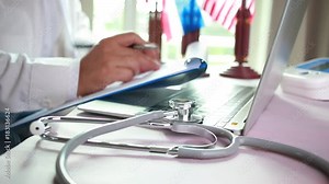 Doctor's writing and working on laptop computer, writing prescription clipboard with record information paper folders on desk in hospital or clinic, Healthcare and medical concept. Focus stethoscope