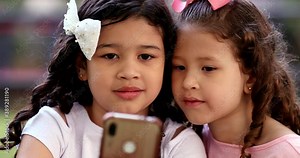 Small little girls staring at cellphone screen