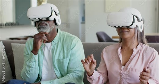 Couple wearing white VR headsets alternating pointing and pinching on couch manipulating 3D objects