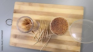 Wood toothpicks in plastic containers on cutting board, top view