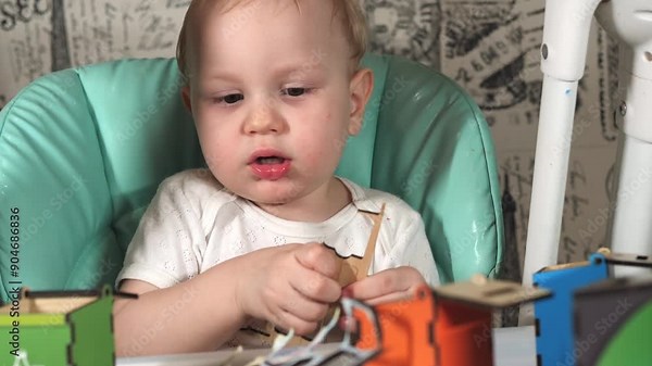 A little boy sits at a children's chair and plays a garbage sorting game