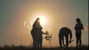 Family planting tree with shovel at sunset. Parents children work together digging soil planting sapling. Tree planting symbolizes growth sustainability family unity. Family tree planting with shovel.