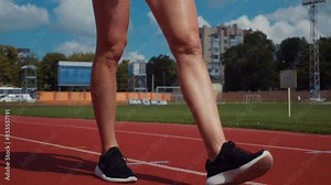 Young woman stretching on track, preparing for workout. Fitness enthusiast limbering up on running track. Woman in active wear stretching before exercise session. Track athlete warming up