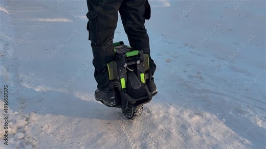 Person riding electric unicycle monowheel self-balancing personal transportation device on snowy winter terrain showing alternative eco-friendly urban mobility technology outdoor recreation activity