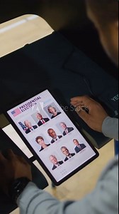 African American man, male voter votes for US presidential candidate in voting booth using tablet computer. US citizen at polling station. Election Day in the United States of America. Vertical shot