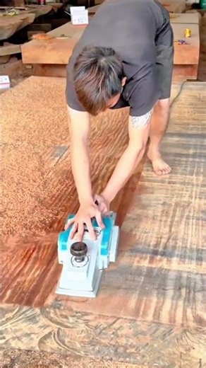 using a power electric planer tool to smooth and level the surface of a large wooden timber board