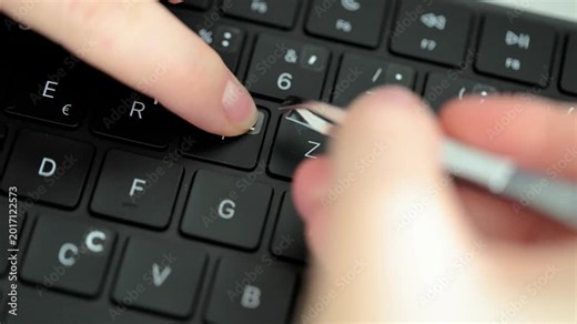 Hands applying letter stickers with tweezers on an English keyboard, adding Cyrillic alphabet characters for multilingual typing