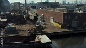 Trucks bringing loose material to transhipment point in industrial site. Dumping load on ground. New York City, USA