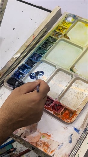 A serene watercolor landscape captures the timeless beauty of nature — an old house nestled among tall, whispering trees on the mountain slopes. The misty blue mountains fade gently into the distance, creating a dreamy depth that draws the viewer’s eye. Soft washes of green and earthy browns blend harmoniously, while the sky glows with warm hues of sunrise, casting golden light over the rustic house. The texture of the old wooden walls, the delicate shadows of the trees, and the flowing watercol