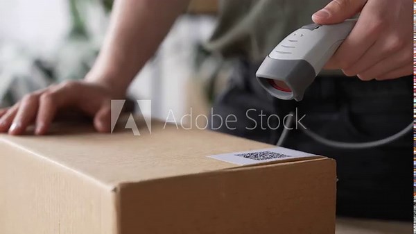 Warehouse worker using a QR code reader, scanning parcels into the system, worker checking goods packages and making inventory of goods