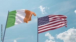 Ireland flag and the USA flag on a flagpole realistic wave on strong wind in blue sky. Irish Free State and The United States of America