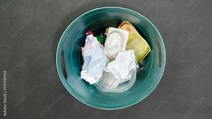 Plastic trash can being filled with household garbage and food leftovers, stop motion