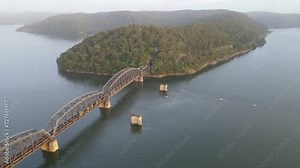 Aerial drone view of Hawkesbury River Train Bridge on the Hawkesbury River, NSW Australia showing a train travelling over the railway bridge during the early morning in February 2024