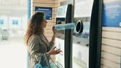 Woman recycling plastic bottle via reverse vending machine