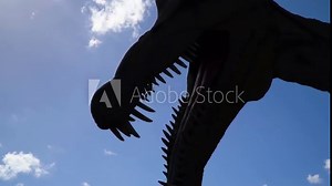 close up silhouette head of dinosaur and big teeth scary terrifying scene ancient historical animal bright sky with clouds slow motion