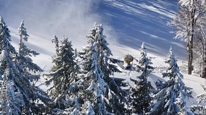 Snowmaker cannon on a winter mountain slope in a ski resort. Aerial 4K video of this machine used to create snow on ski and snowboard slopes. Winter sports.