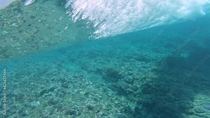 SLOW MOTION, UNDERWATER: Spectacular barrel wave breaking and rolling over the Pacific ocean reef. Amazing crystal clear tube wave rolls towards the tropical coasts of Fiji on a beautiful summer day.