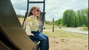 Child plays on wooden swing. Child swing, kid girl smile. Child girl happiness dream entertainment. Happy little girl swings on swing in park. Family walk