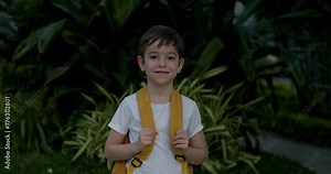 Portrait handsome child of a happy cute school boy, a smiling school boy. Cute little boy with a backpack, standing alone on a sunny street outdoors, a handsome face primary one grade student. 4 K.
