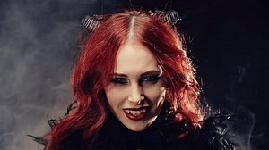 Portrait witch girl with red hair and devil horns. Woman smiling devilishly and laughing. Concept of cult of dark forces, rituals for summoning demon, halloween, occultism, esoterics.