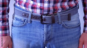 Man is touching his dick in jeans and slapping by hand. Playful mood, hand closeup. He is wearing jeans and plaid shirt, waist closeup.