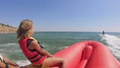 rear view of a blonde girl child in a life jacket sitting on a banana...