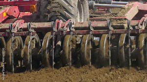 Working parts of new modern agricultural disc harrow. Tillage equipment. Tractor seeder in the field sows grains of wheat or oats for growing grain products. Close-up, rear view.
