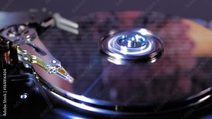 The hdd working, the heads moves over the disks, the film is beginning and frames combined with the symbols of the program encoding are reflected on the surface of the disk. Macro. Closeup