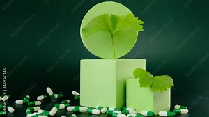 Ginkgo biloba .Green homeopathic capsules with ginkgo extract and ginkgo biloba leaves on green background. Alternative medicine and homeopathy.