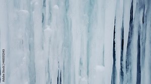 The texture of frozen water in natural settings. A frozen waterfall with icicles during severe frosts in the Arctic latitudes. blue ice wall