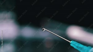 Learstvo is dripping from medical syringe, flowing down in large drops close-up. Nurse prepares syringe for injection to patient. Doctor uses hypodermic needle and to inject the drug as treatment.