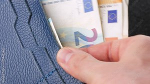 A closeup view of cash being stored in a blue wallet for financial purposes